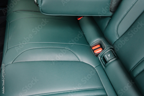 Installing ISOFIX baby and car seat for maximum safety. Part of green perforated leather car seat. Fastening child seat with isofix system. Luxury car inside. Interior of prestige modern electric car. © Serhii