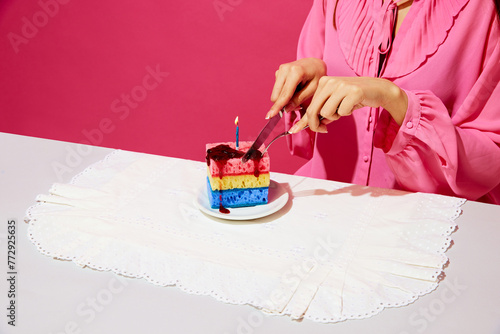 Cropped image of woman in pink shirt sitting at table and cutting birthday cake made of dishwashing sponges and candle. Birthday party. Concept of food pop art photography, creativity, quirky style photo