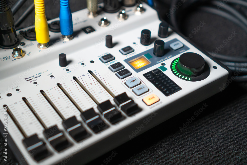 Close-up image of hand adjusting mixer knob for volume control during live studio performance. Mixer features multiple knobs and buttons for precise audio mix adjustments. Close-up image of hand adjusting mixer knob for volume control during live studio performance. Mixer features multiple knobs and buttons for precise audio mix adjustments.