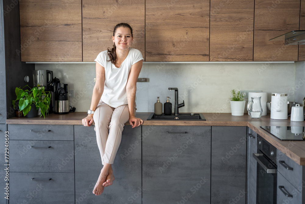 Young woman sitting on her kitchen counter at home Young woman sitting on her kitchen counter at home