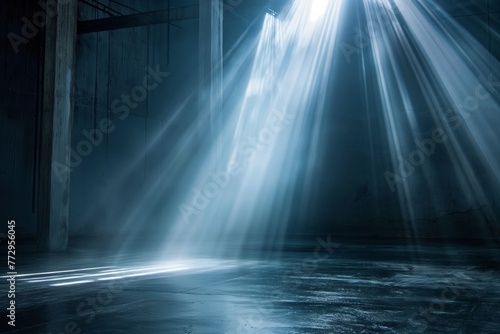Rays of light penetrating a dark, empty industrial interior.