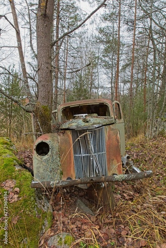 Front grill of a old abandoned rusty car in forest in autumn. photo