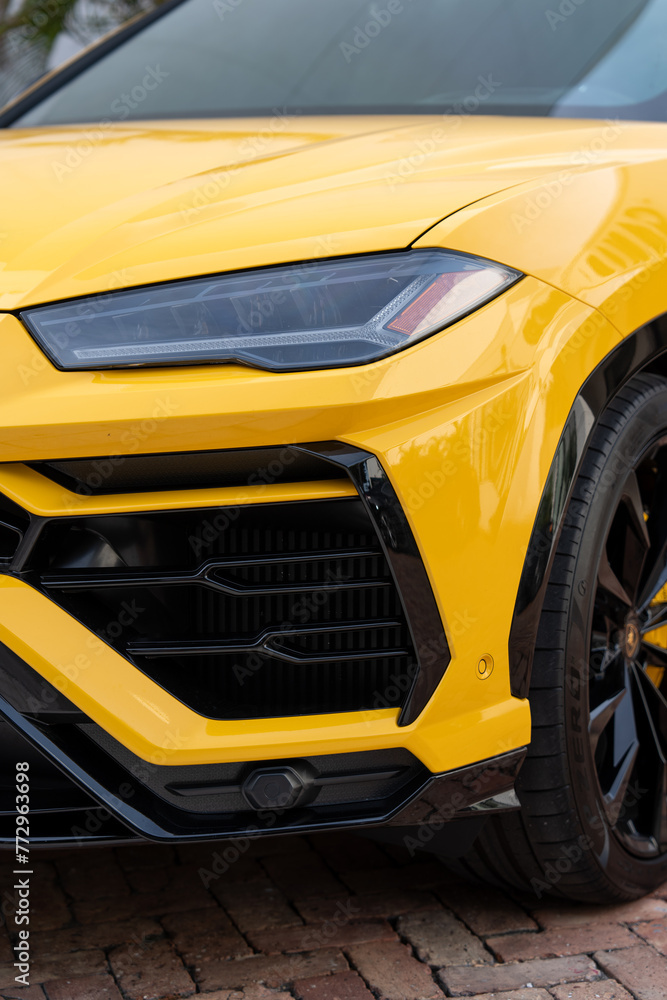 Cropped view of radiator grille and headlight on front bumper of yellow stylish car. Modern ventilation and cooling systems on massive off-road vehicle parked on paving stones Cropped view of radiator grille and headlight on front bumper of yellow stylish car. Modern ventilation and cooling systems on massive off-road vehicle parked on paving stones