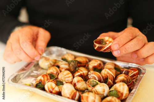  a man tries a French dish of baked snails. Hot food