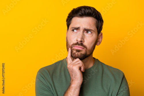 Photo of doubtful unsure man wear khaki t-shirt finger chin looking empty space isolated yellow color background