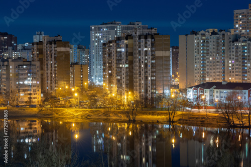 Night cityscape of the big city. Bright  multi colored light on empty streets. Apartment buildings in bedroom town area. Kyiv in end of march 2024. Ukraine.