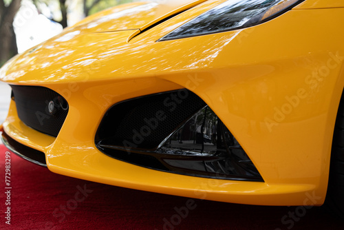 Close up of low plastic bumper equipped with powerful headlights and elegant radiator. Futuristic shape of racing car designed for fast and dynamic driving © port-o