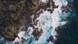 View from drone of Atlantic ocean with strong swell beating against the rocky cliff in Tenerife south coast, blue rough sea with big waves with foam crashing against the rocks, Canary island