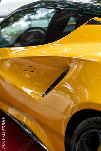 Automobile body with technological air intake systems on both side of doors and sleek shape of roof. Unique style of powerful racer car in rich yellow color with smooth polished surface