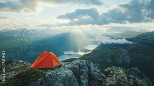A tent pitched on a rocky ledge overlooking a valley, with a breathtaking view of the landscape below. 