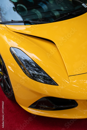 Elegant shape of shiny headlight on bright yellow body of expensive car. Innovative vehicle demonstrated as technological advancement in automotive production