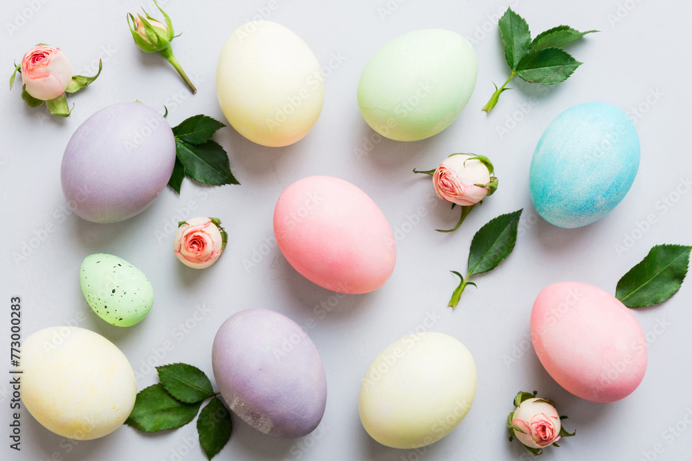 Happy Easter. Easter eggs on colored table with yellow roses. Natural dyed colorful eggs background top view with copy space Happy Easter. Easter eggs on colored table with yellow roses. Natural dyed colorful eggs background top view with copy space