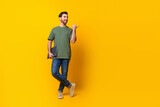 Full size photo of handsome young guy hold netbook point look empty space wear trendy khaki outfit isolated on yellow color background