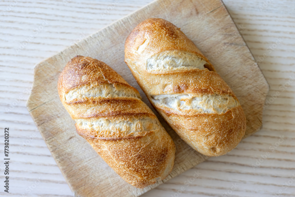 Crusty golden brown bread loaves on wooden cutting board Crusty golden brown bread loaves on wooden cutting board
