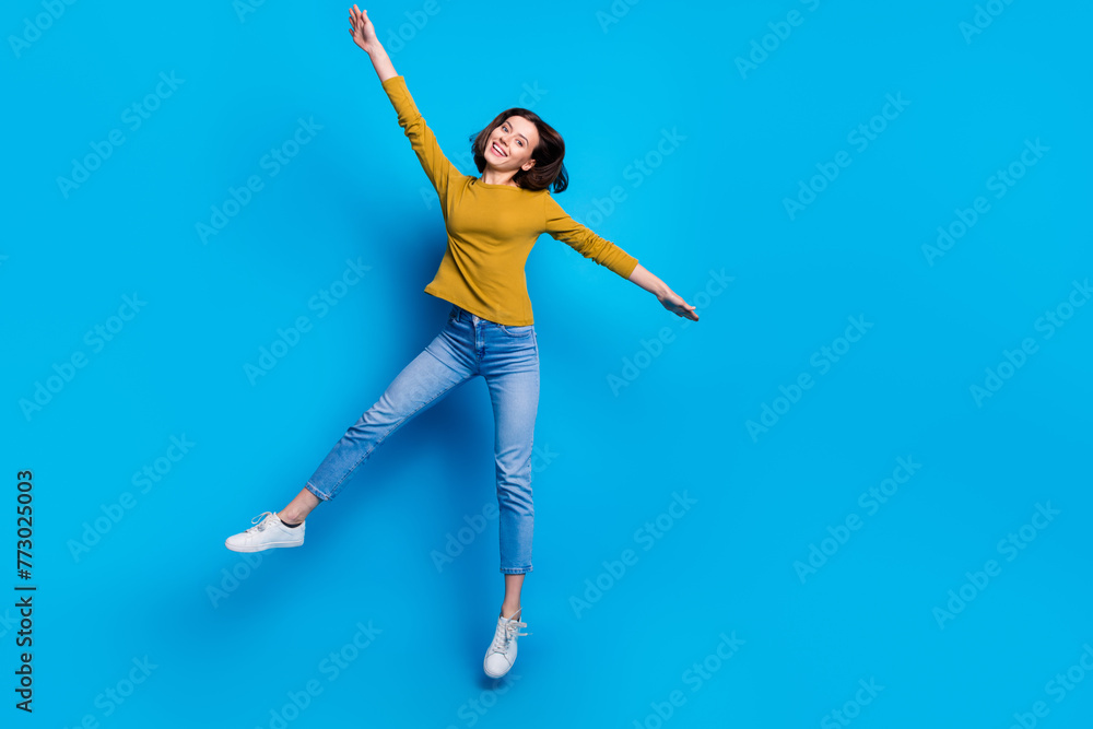 Obraz premium Full length photo of cheerful cute lady dressed shirt jumping high rising hands arms empty space isolated blue color background