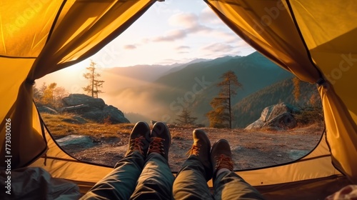Legs of couple hiker relaxing inside a tent with Rocky Mountains and wooden hut on autumn forest in national park
