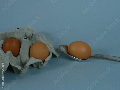 A tight shot on some eggs. An egg on a spoon and some eggs in an open box. March 1, 2024 - Paris, France. © Yann Vernerie
