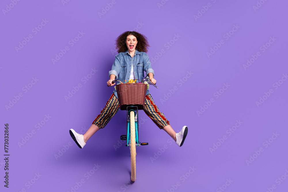 Full size portrait of pretty young woman ride bike empty space ad wear denim shirt isolated on purple color background Full size portrait of pretty young woman ride bike empty space ad wear denim shirt isolated on purple color background