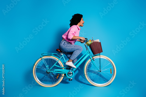 Full length side profile photo of astonished girl dressed shirt riding bike staring at crash empty space isolated on blue color background © deagreez