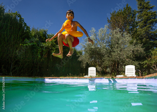 Sunny poolside fun with jumping teen boy captured in motion