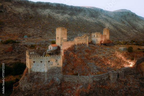 An ancient Khertvisi fortress stands proudly on a high hill, overlooking a stunning natural landscape of mountainous landforms