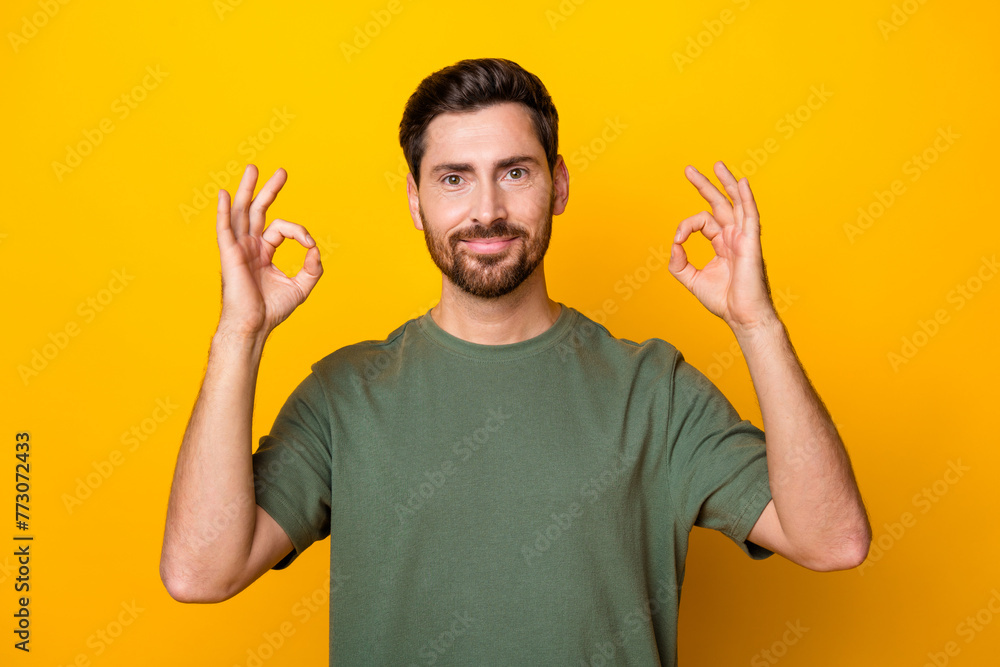 Photo of confident good mood man wear khaki t-shirt showing two okey signs isolated yellow color background Photo of confident good mood man wear khaki t-shirt showing two okey signs isolated yellow color background