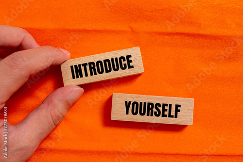 Introduce yourself words written on wooden blocks with orange background. Conceptual symbol. Copy space. photo