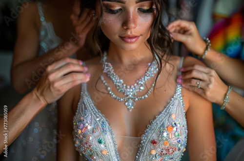 Detailed shot of bride in glittering dress being adorned with intricate jewelry photo