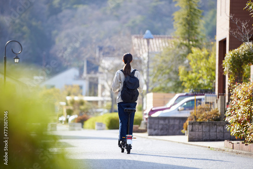 住宅街を電動キックボードで移動する日本人の女性 photo