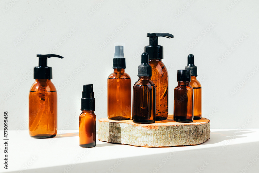 Set of natural cosmetics. Amber bottles with facial, bath liquid on wooden bar on a concrete background. Front view Set of natural cosmetics. Amber bottles with facial, bath liquid on wooden bar on a concrete background. Front view