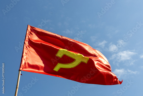 Large communist flag floating in the wind with a blue sky