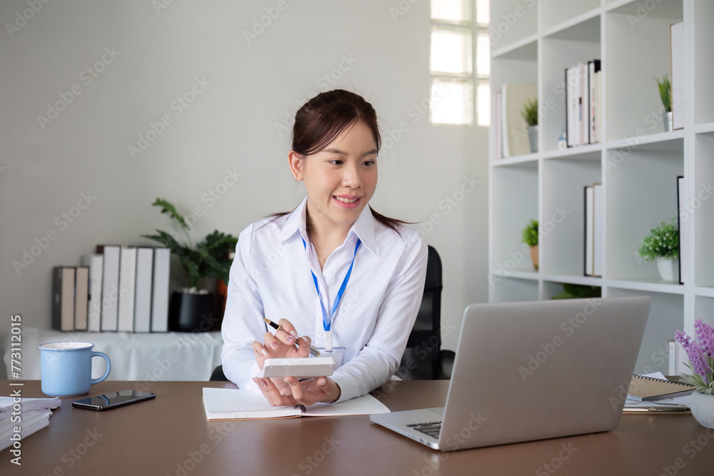 Young Asian accountant sitting and calculating finances Expenses and taxes on laptop in office Young Asian accountant sitting and calculating finances Expenses and taxes on laptop in office