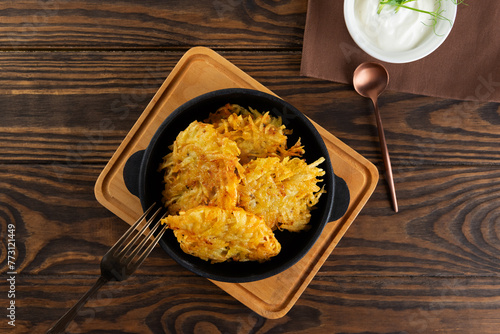 Potato pancakes, draniki, Latkes or Levivot in a cast iron frying pan with sour cream. Hanukkah, Passover food. Top view. photo