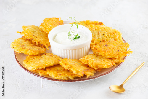 Latkes or Levivot, potato pancakes, draniki with sour cream and green pea microgreens. Hanukkah food. During the Jewish Festival of Lights holiday. photo