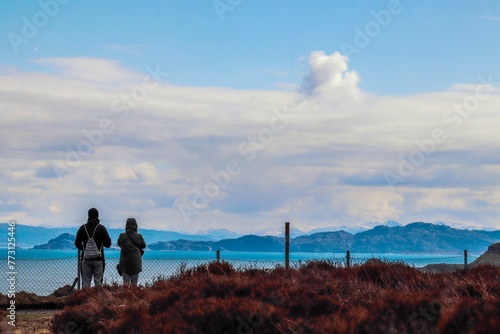 Rear view of a couple looking at a lake and mountain view in Isle of Skye, Scotland, UK
