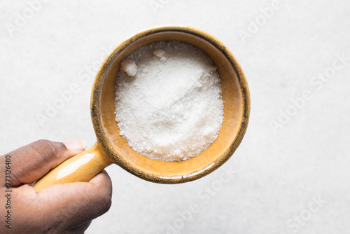 A bowl of white sugar, top view of granulated sugar in a brown bowl