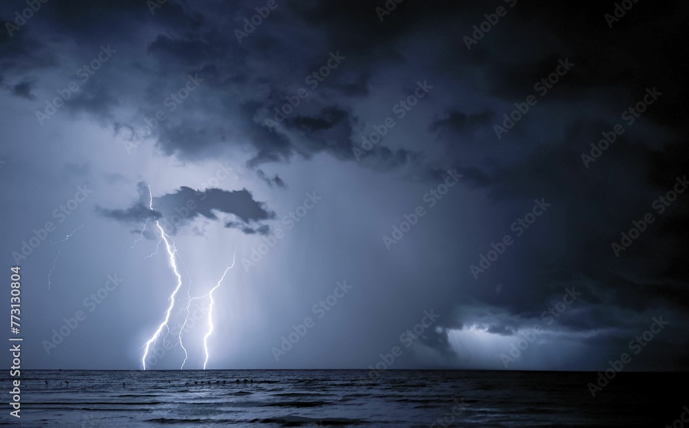 Dramatic image of a thunderstorm, the lightning illuminating the dark clouds over the ocean