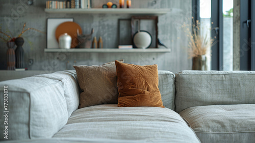 Grey sofa with brown pillow against concrete wall with shelves. Loft home interior design of modern living room. Contemporary Scandinavian design.