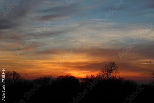 Orange sunset from a hilltop with clouds in the background © Wirestock