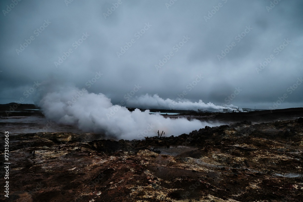 steaming steam rises from a crater with dark clouds overhead in the background