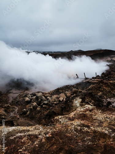 Stunning landscape of a volcanic crater with billowing steam rising from the center and dark clouds