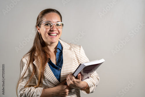 Mujer estudiante sosteniendo sus notas y libros mientras sonrie a cámara. photo