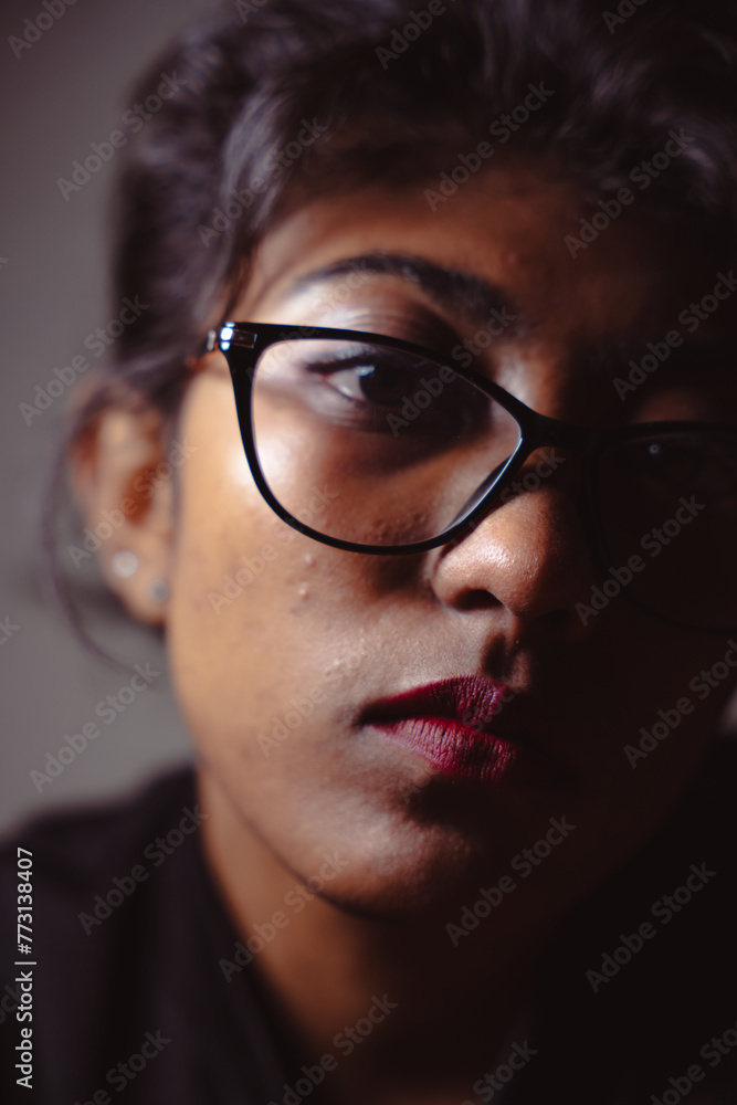 A woman with glasses and red lipstick is looking at the camera