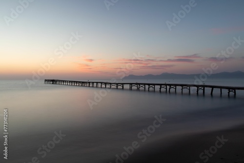 a pier is shown at the edge of the water during sunset