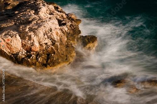 waves and rock in a body of water near the shore