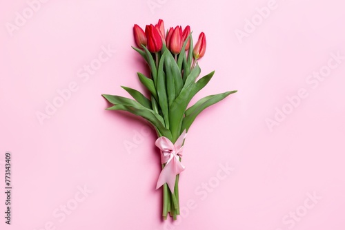 Closeup of a red tulip bouquet with a ribbon isolated on pink background © Wirestock