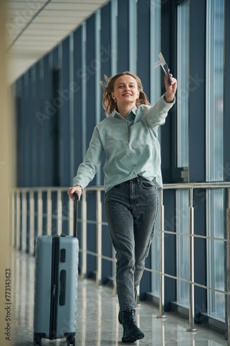 Running with tickets in hands. Young woman in airport hall