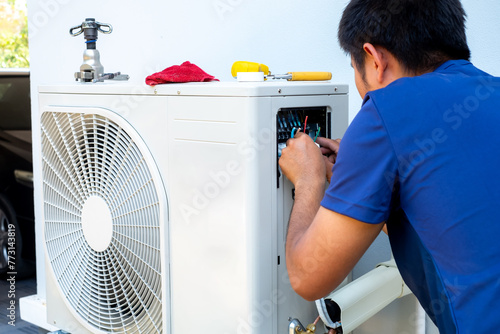 Male technician installing outdoor unit of air conditioner  to cool the household in the summer. air compressor, electronic, hot summer, high temperature, Tropical countries