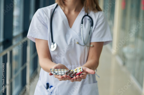 Bunch of pills in hands. Female doctor in white coat is in the hall