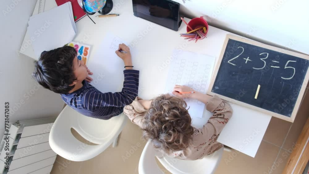 Two brothers sit together at the table, pencils scratching against paper as they tackle their homework. They lean in, heads close, discussing math problems and reading assignments. Two brothers sit together at the table, pencils scratching against paper as they tackle their homework. They lean in, heads close, discussing math problems and reading assignments.